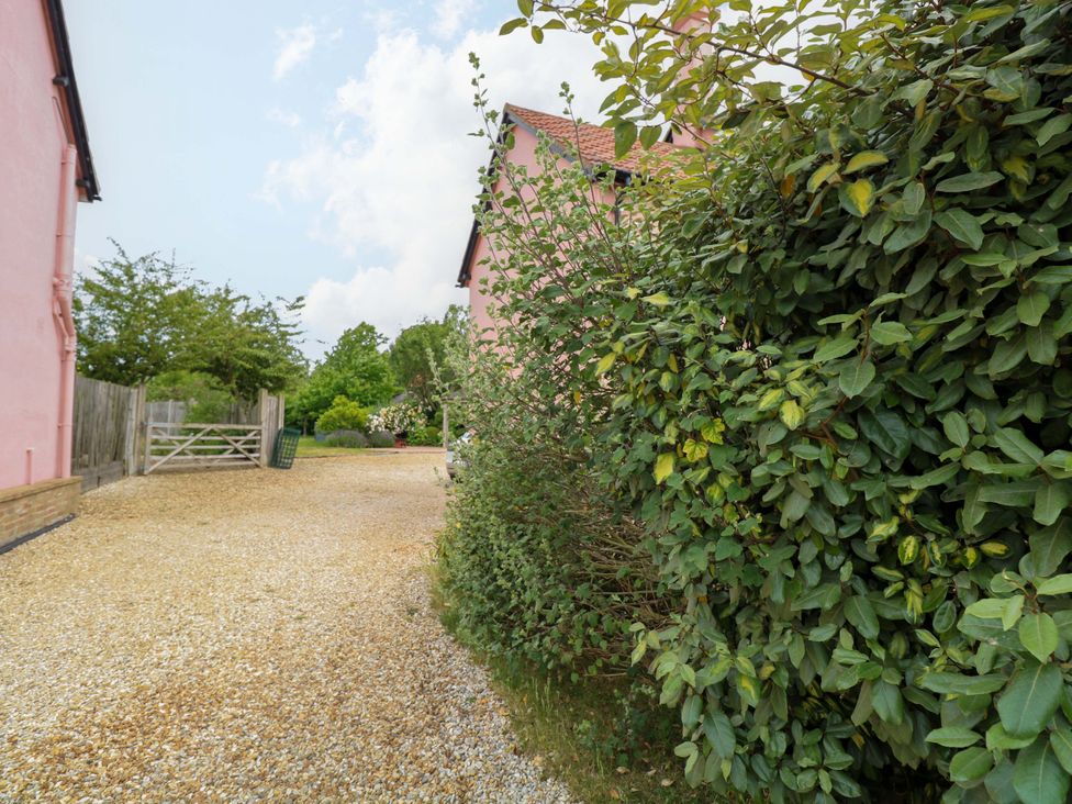 An outdoor area with a gravel driveway and green bushes at The Mallows in Walsingham