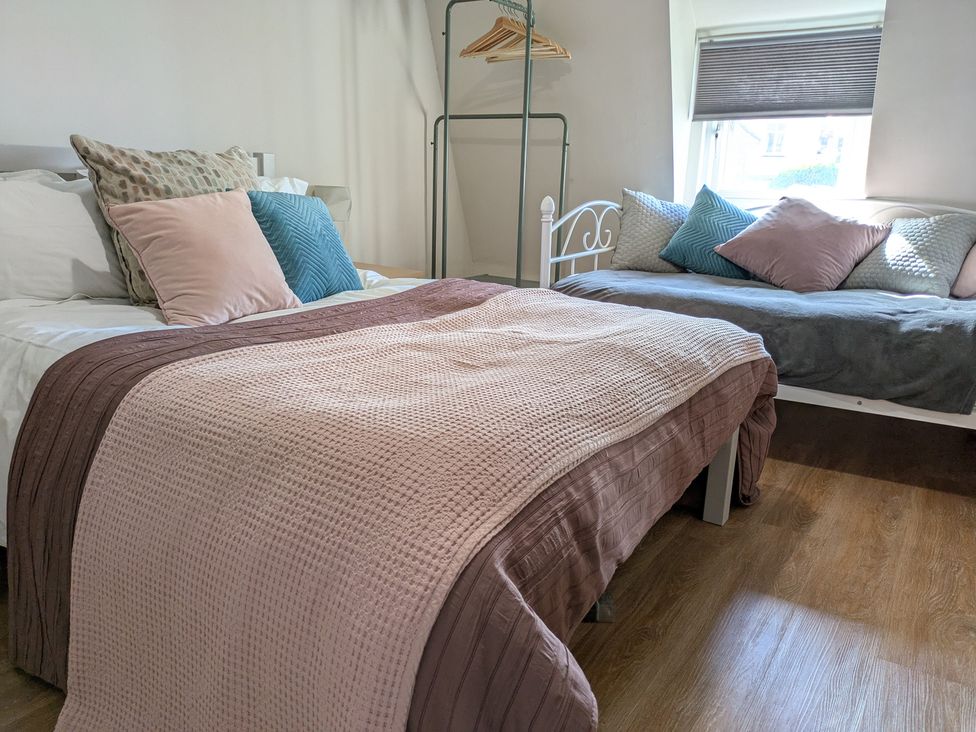 A bedroom with a bed and sofa with cushions at Melita in Curry Rivel