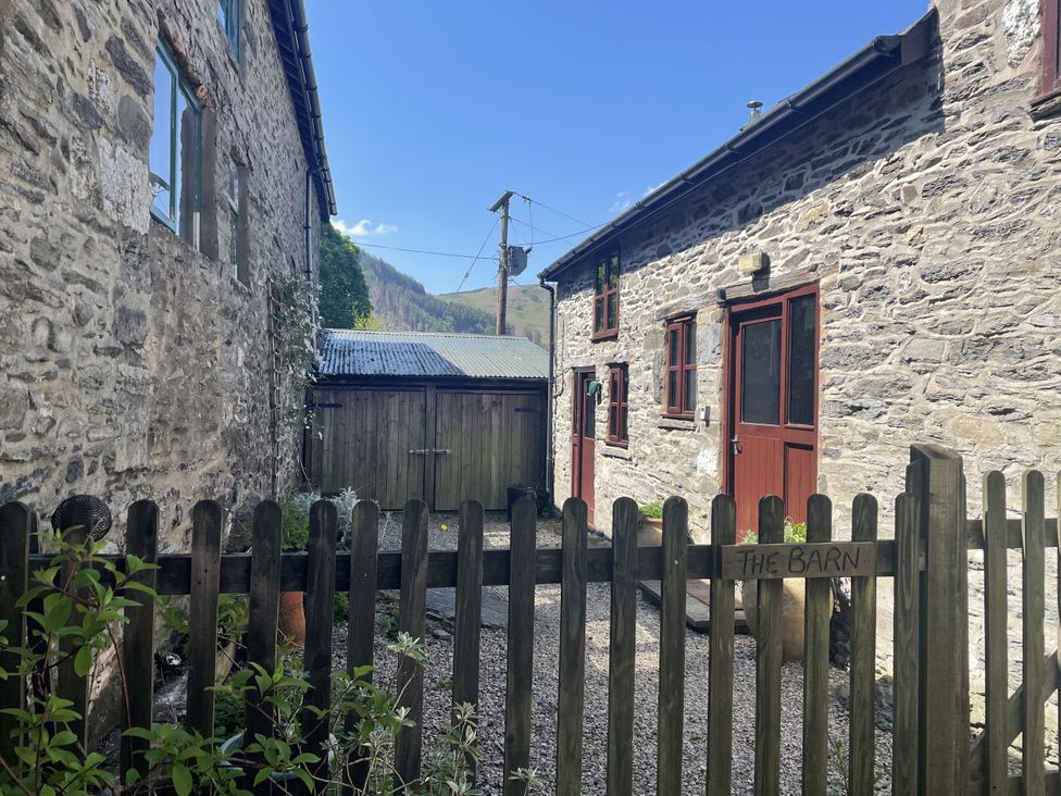 An outdoor area with stone buildings and a wooden fence at Graig Las The Barn Llangynog near Llanrhaeadr-Ym-Mochnant