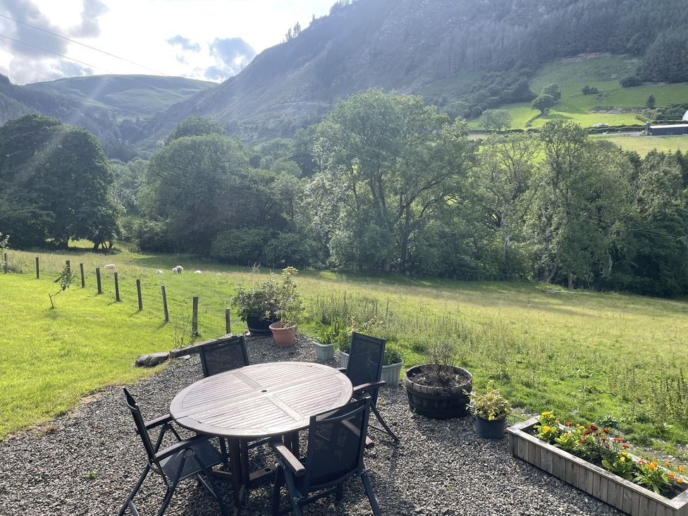 A terrace with a table and chairs overlooking a field at Graig Las The Barn Llangynog near Llanrhaeadr-Ym-Mochnant