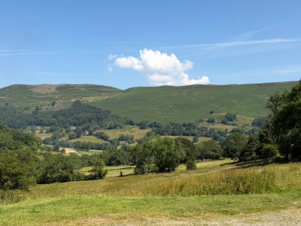 A landscape view of hills and trees with blue sky at Graig Las The Barn in Llangynog near Llanrhaeadr-Ym-Mochnant