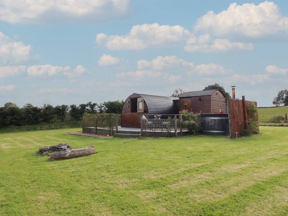 A cabin surrounded by grass and trees at Embden Pod at Banwy Glamping Llanfair Caereinion