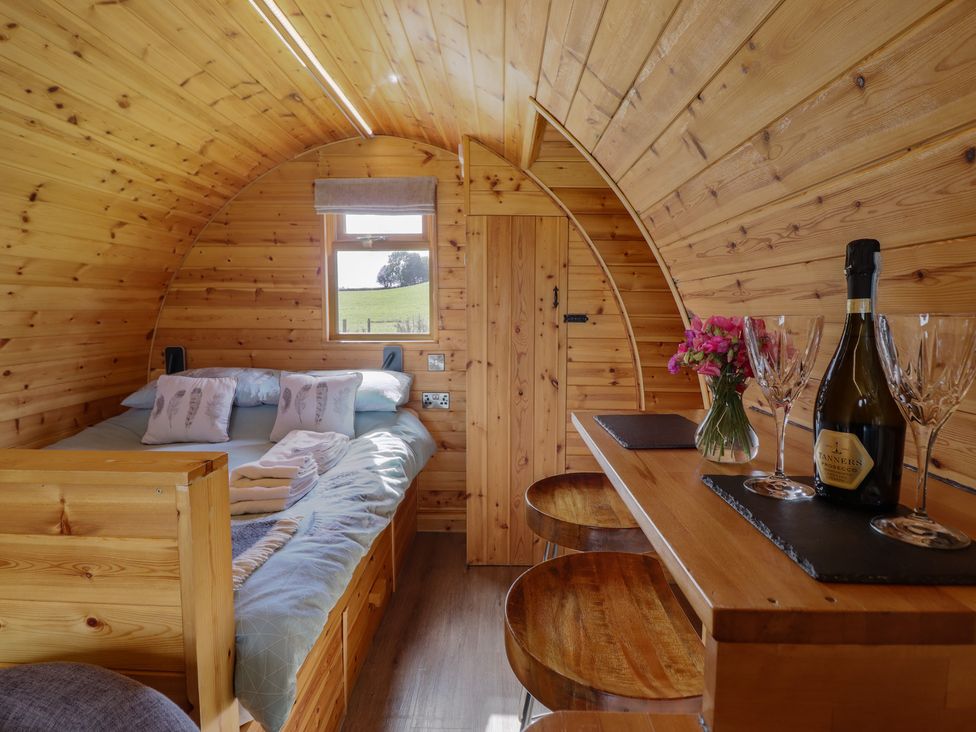 A sleeping area with bed and table at Embden Pod at Banwy Glamping Llanfair Caereinion
