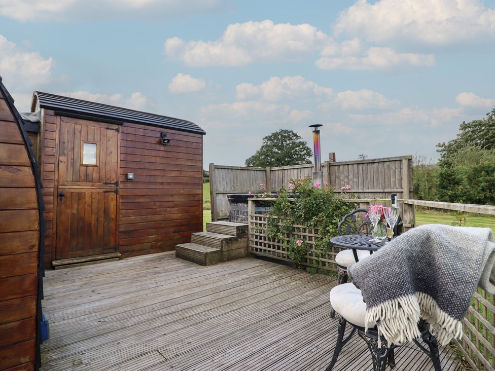 An outdoor space with a wooden shed, a table, and chairs at Embden Pod at Banwy Glamping, Llanfair Caereinion