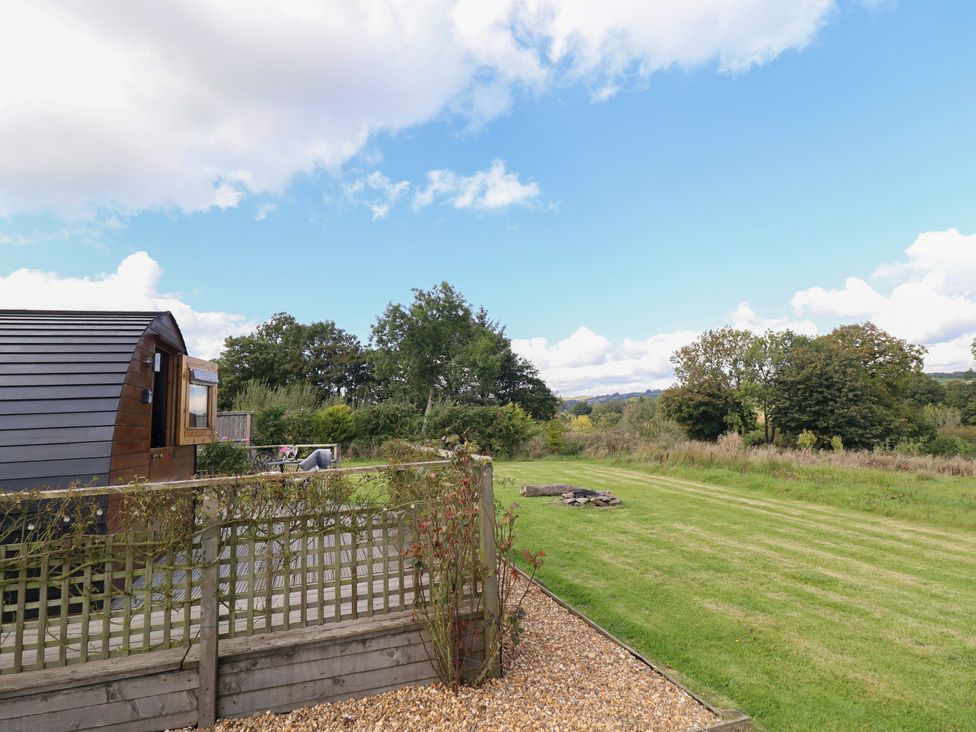 An outdoor view with a glamping pod and grassy area at Embden Pod at Banwy Glamping Llanfair Caereinion