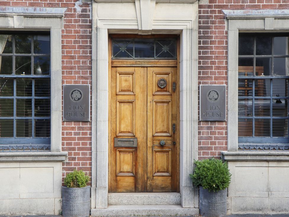An entrance with a wooden door and brick wall at Lion House in Moretonhampstead