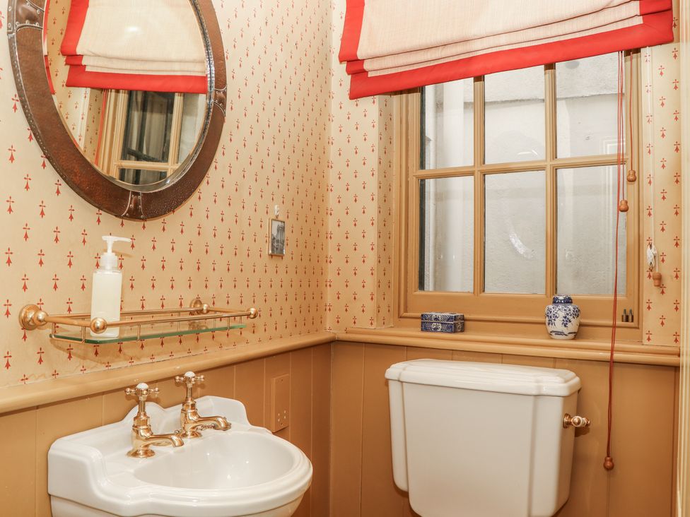 A bathroom with a sink, toilet, and mirror at Lion House in Moretonhampstead