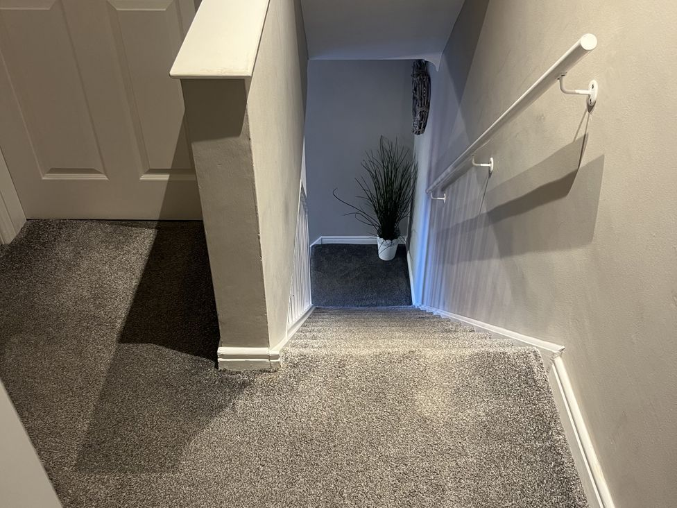 A staircase with a handrail and a plant at Honeysuckle Cottage in Richmond