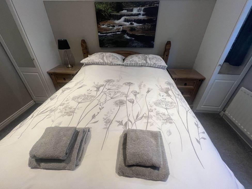 A bedroom with a bed and bedside table at Honeysuckle Cottage in Richmond