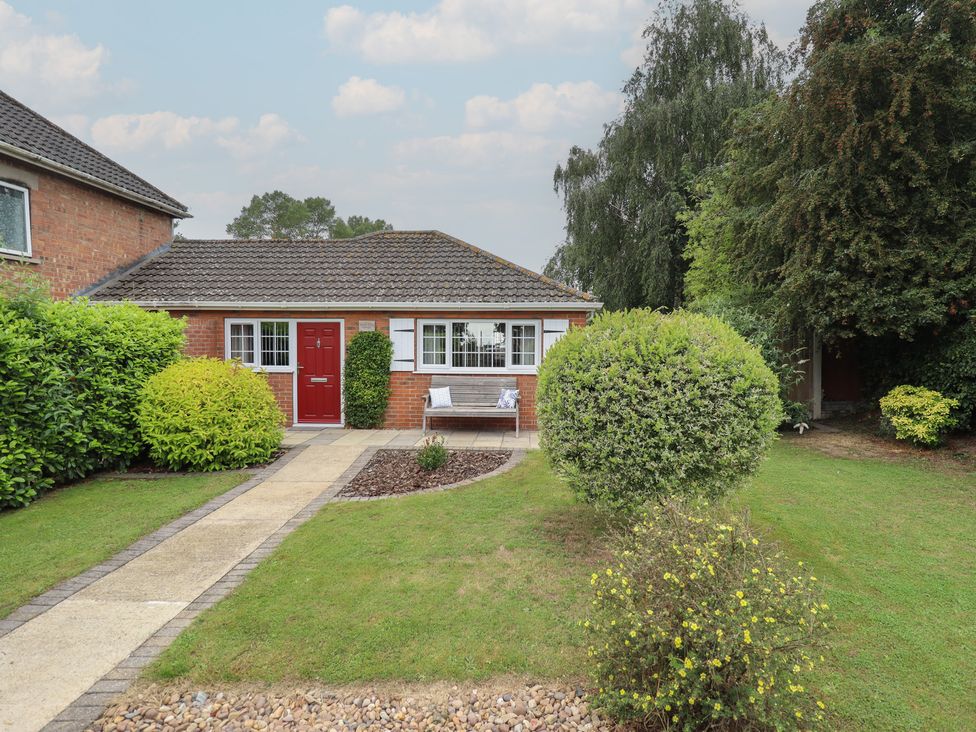 A house with a red front door and garden at Marsh View Cottage in Wainfleet All Saints