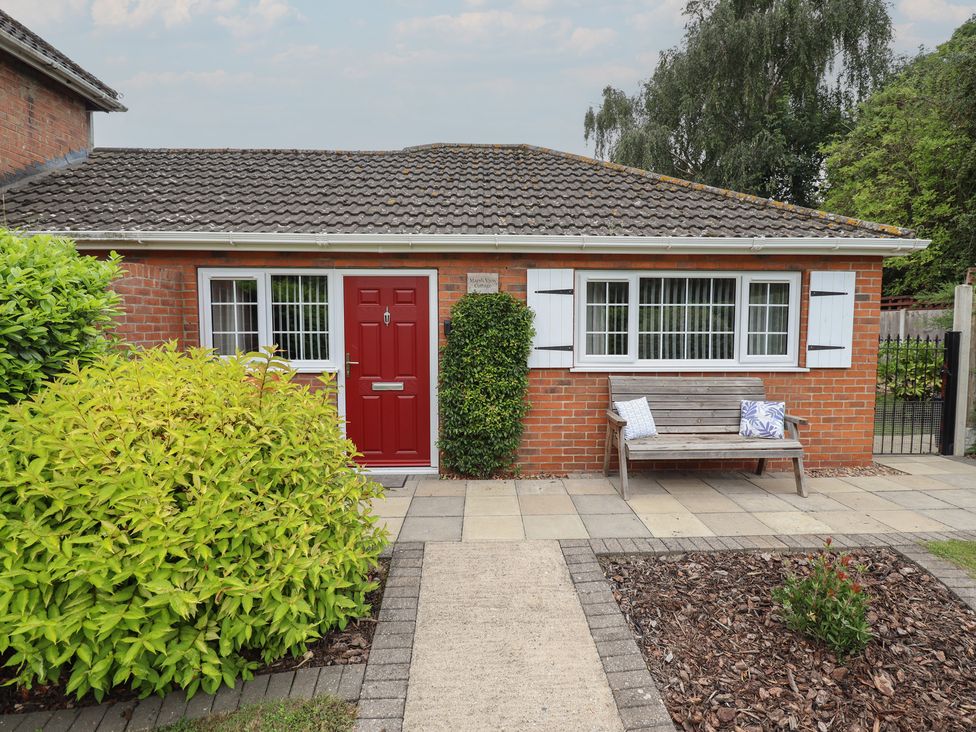 A front view of a cottage with a red door and a bench at Marsh View Cottage Wainfleet All Saints