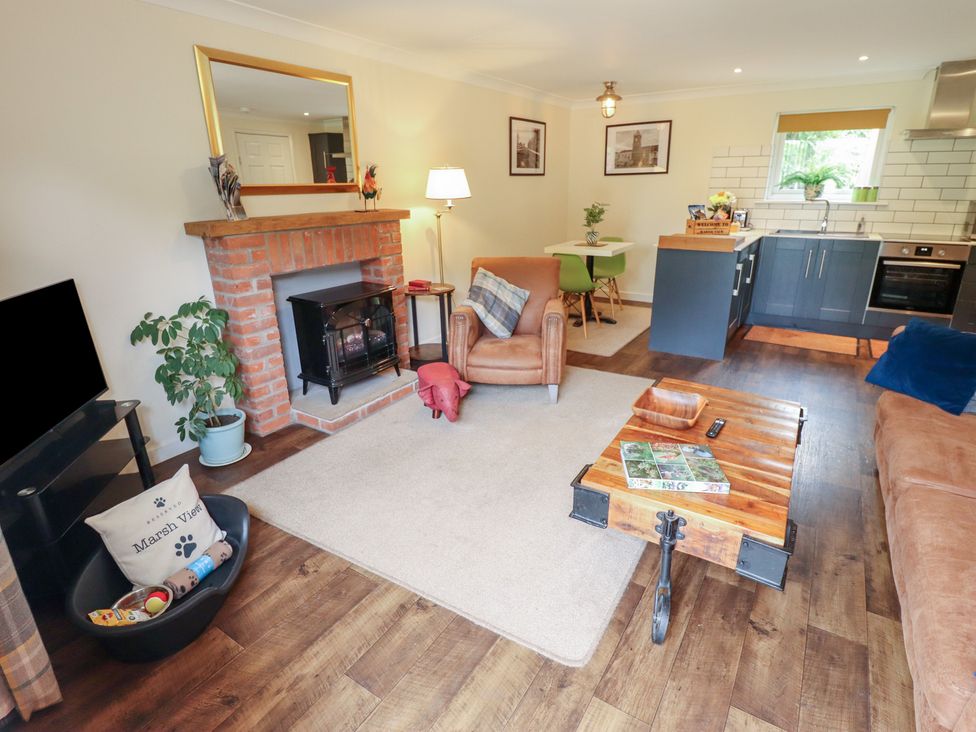 A living room with a fireplace and dining area at Marsh View Cottage in Wainfleet All Saints