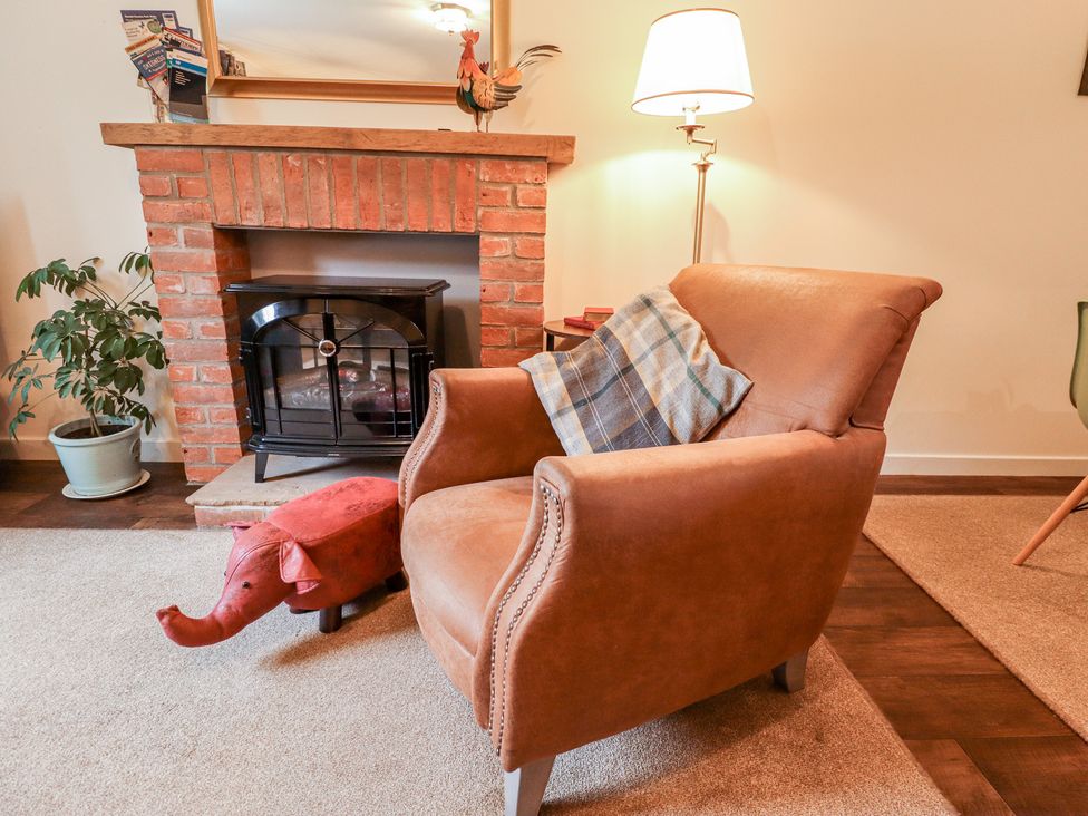 A living room with an armchair and a fireplace at Marsh View Cottage in Wainfleet All Saints