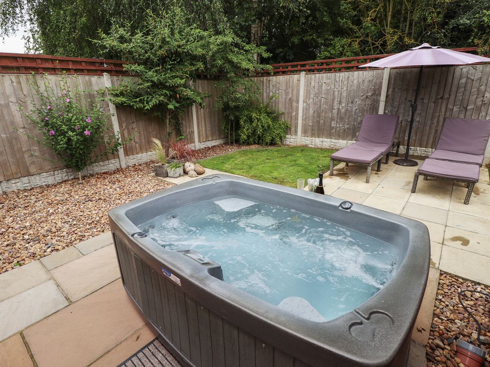 A garden with a hot tub and lounge chairs at Marsh View Cottage in Wainfleet All Saints
