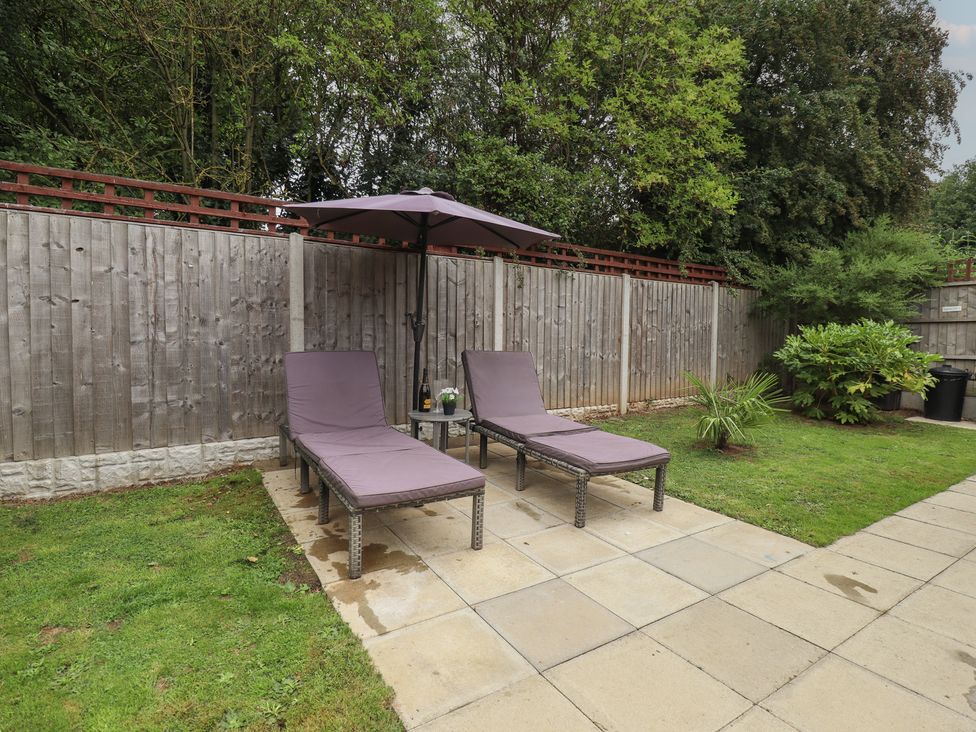 A garden area with sun loungers and an umbrella at Marsh View Cottage in Wainfleet All Saints