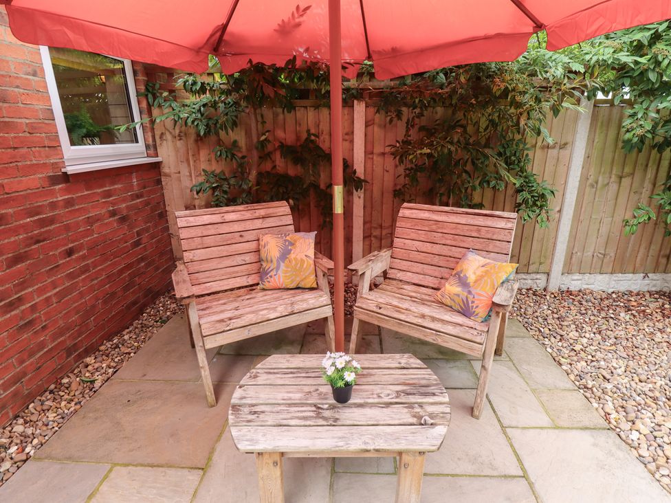 A garden area with two chairs and a table under an umbrella at Marsh View Cottage in Wainfleet All Saints
