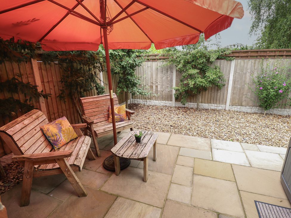 A garden with wooden chairs, a table, and an umbrella at Marsh View Cottage, Wainfleet All Saints