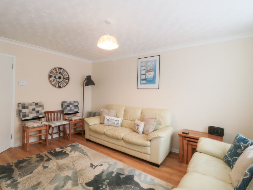 A living room with a clock and a sofa at Jay Cottage in Weymouth