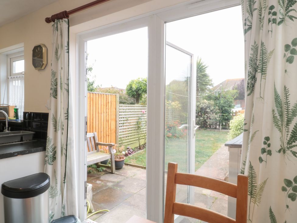 A kitchen with a sink and doors leading to the garden at Jay Cottage in Weymouth