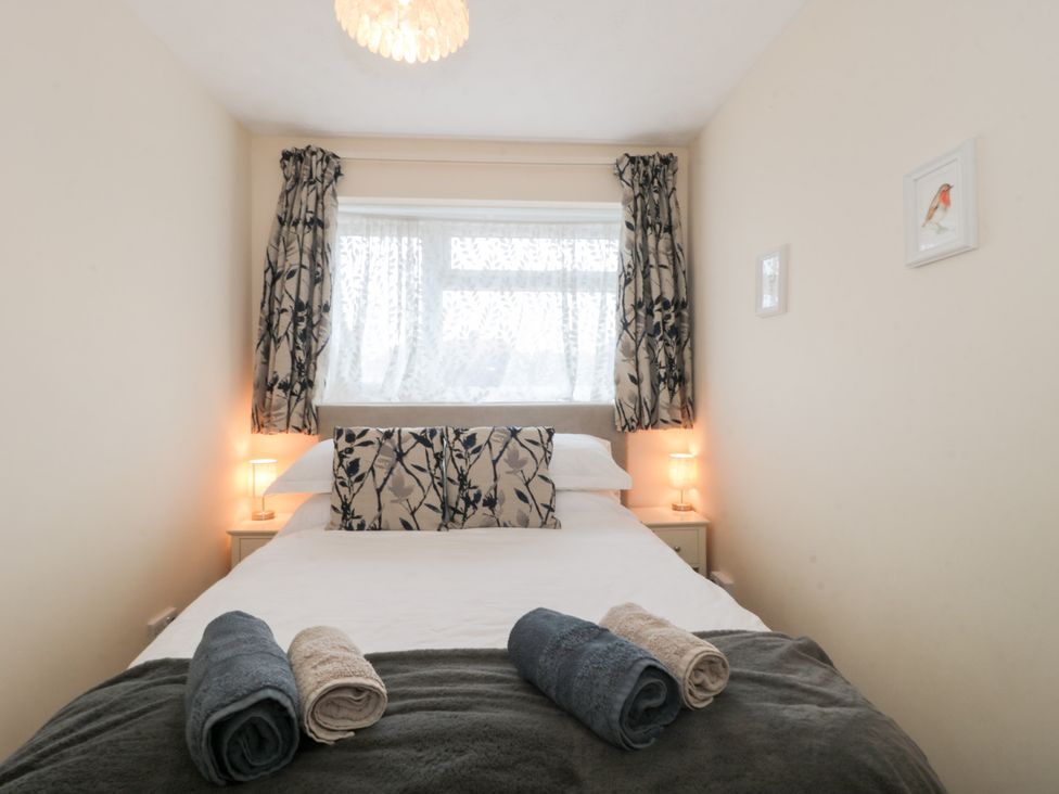 A bedroom with a bed and towels on the blanket at Jay Cottage in Weymouth