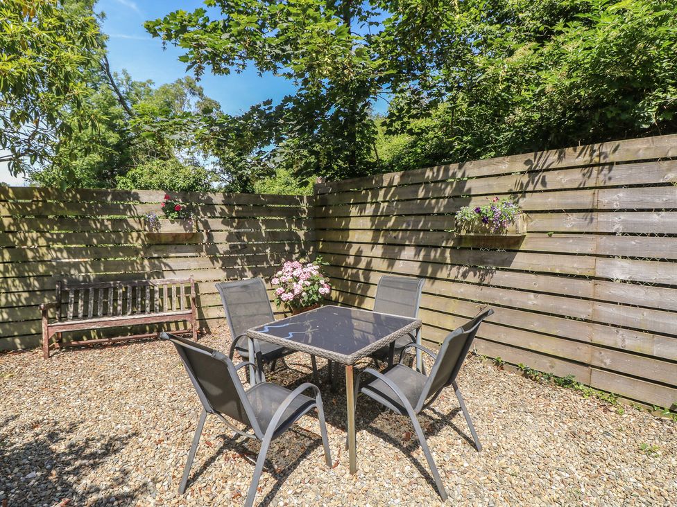A garden with a table and chairs surrounded by wooden fencing at Stable Cottage, Narberth