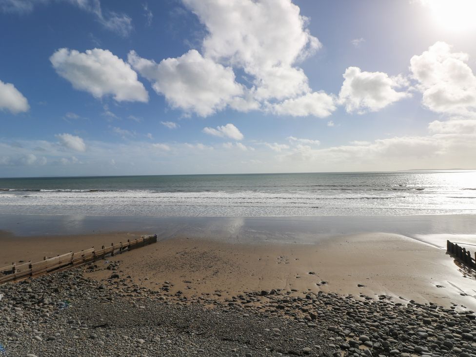 A beach with waves and a wooden pier at Stable Cottage, Narberth