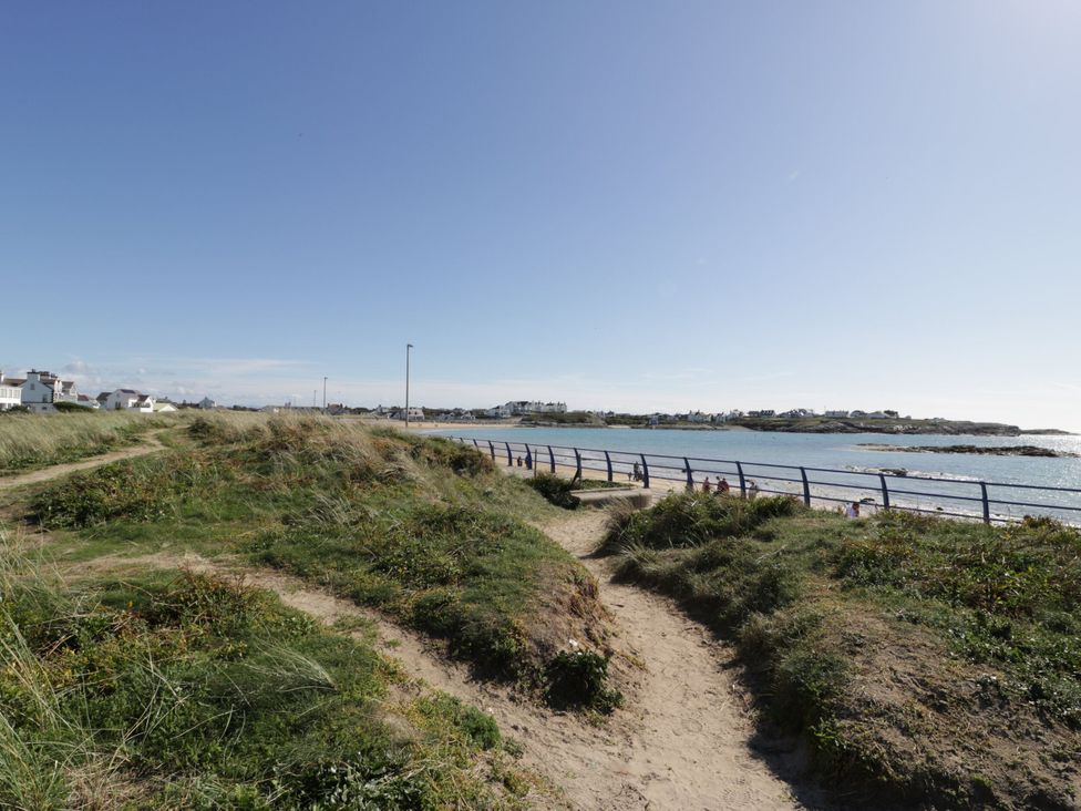 A pathway leading to an ocean with houses in the background at Haul a Gwynt Trearddur Bay