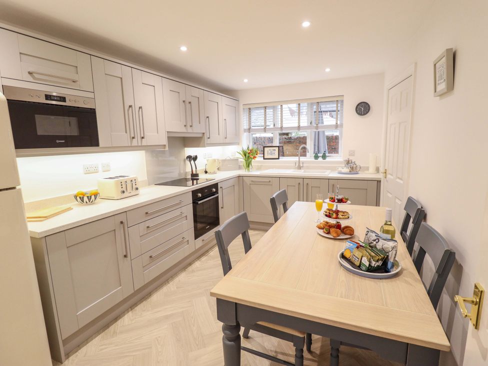 A kitchen with cabinets and a dining table at Armstrong Cottage Beverley