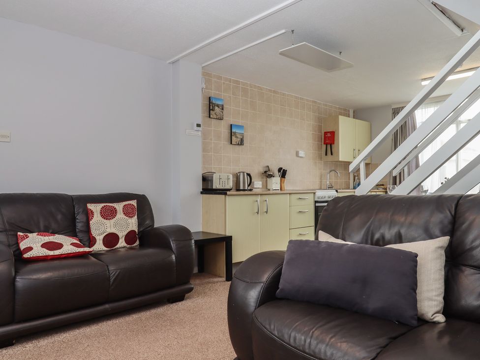A living room with sofas and a kitchen area at Turtle Chalet in Dawlish Warren