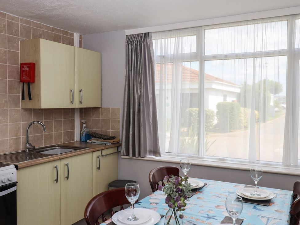 A kitchen with a sink and dining table at Turtle Chalet in Dawlish Warren