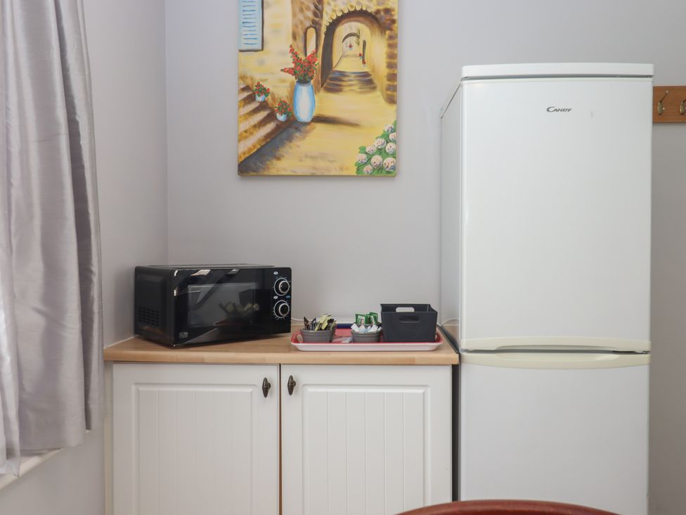 A kitchen area with a microwave and refrigerator at Turtle Chalet in Dawlish Warren