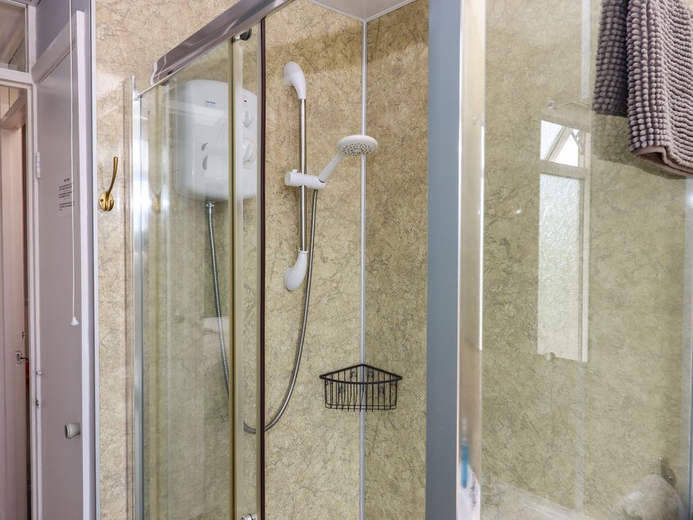 A shower with a towel and soap dispenser at Turtle Chalet in Dawlish Warren