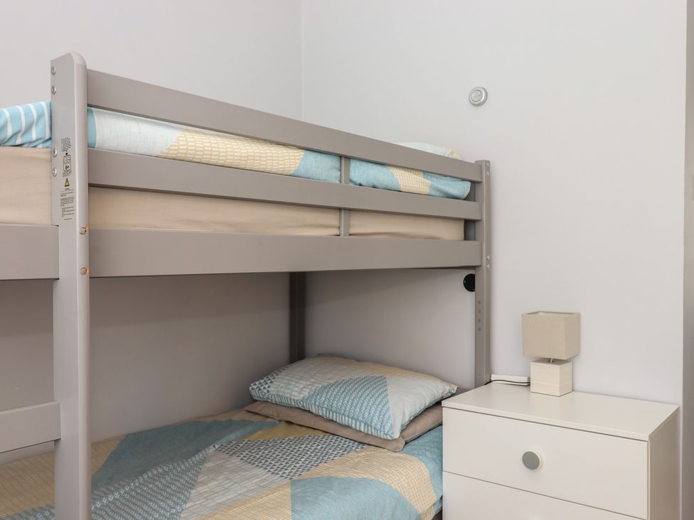 A bunk bed with bedding and a nightstand at Turtle Chalet in Dawlish Warren