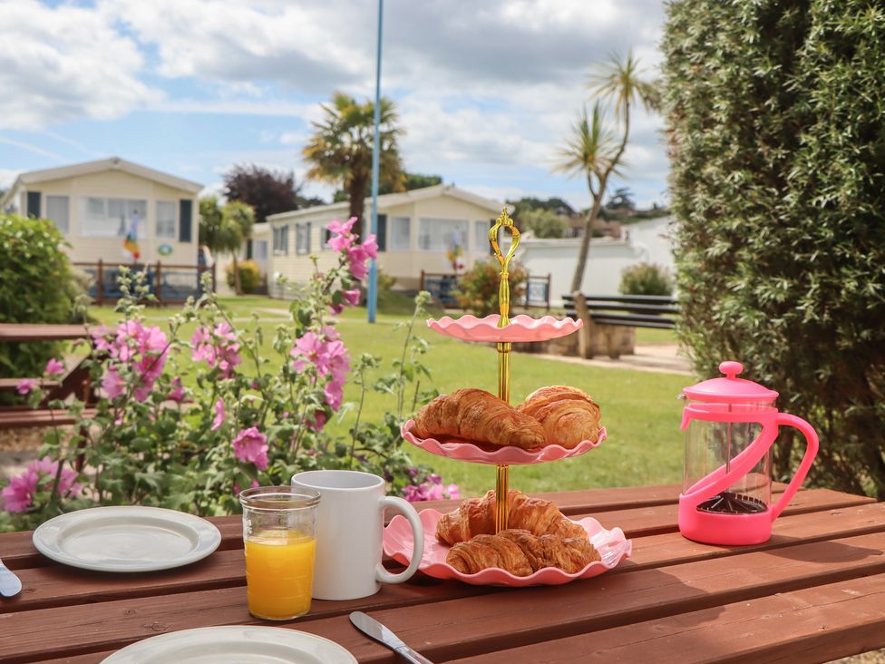 An outdoor dining setup with croissants and drinks at Turtle Chalet in Dawlish Warren