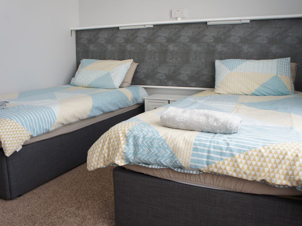 A bedroom with two beds and a towel at Turtle Chalet in Dawlish Warren