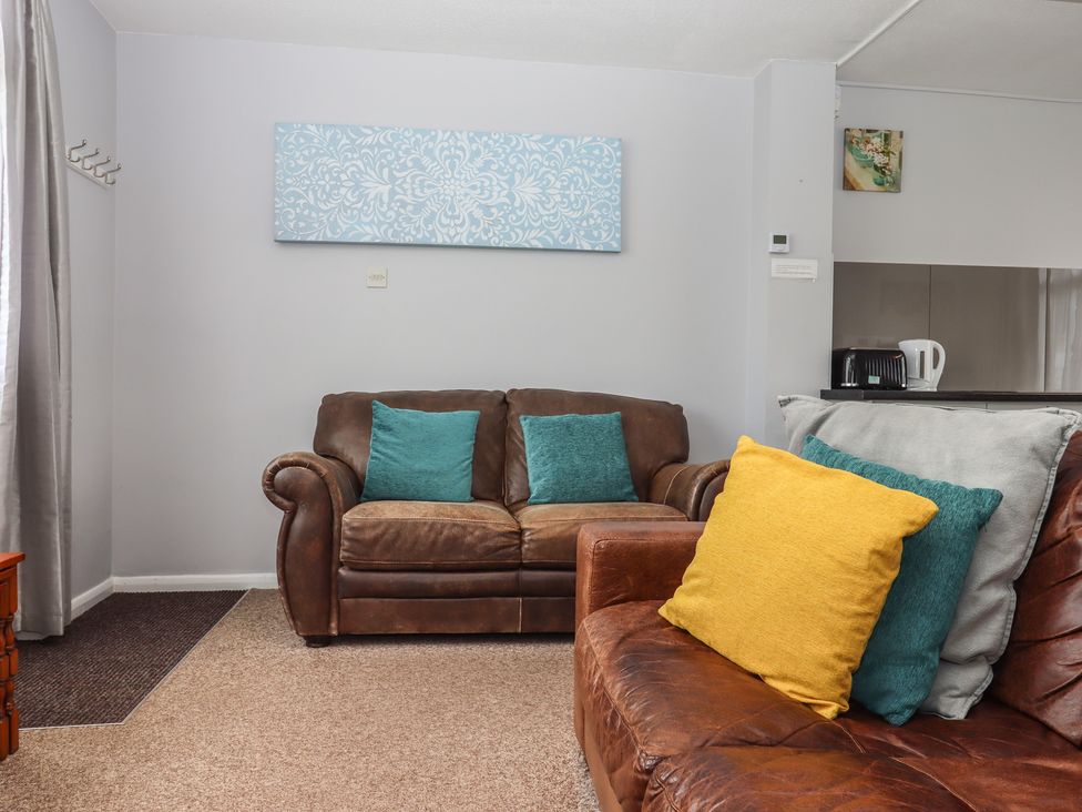 A living room with a sofa, cushions, and wall art at Dolphin Chalet in Dawlish Warren