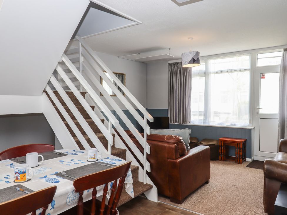 A living room with a dining table and staircase at Dolphin Chalet in Dawlish Warren