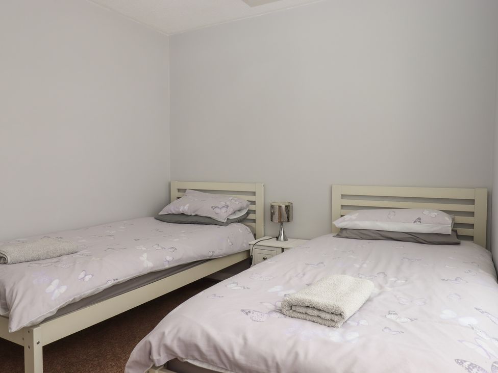 A bedroom with two beds and a bedside table at Dolphin Chalet in Dawlish Warren