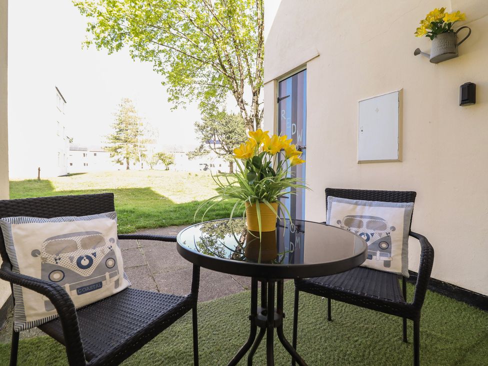 A patio with a table and chairs at Redwood in Harlech
