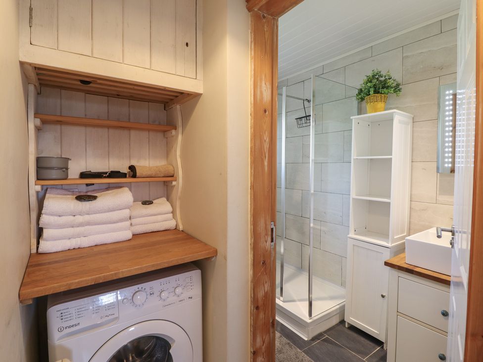 A bathroom featuring a washer, towels, shower, and sink at Redwood in Harlech
