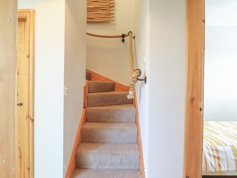 A staircase with a wooden handrail and door at Redwood in Harlech