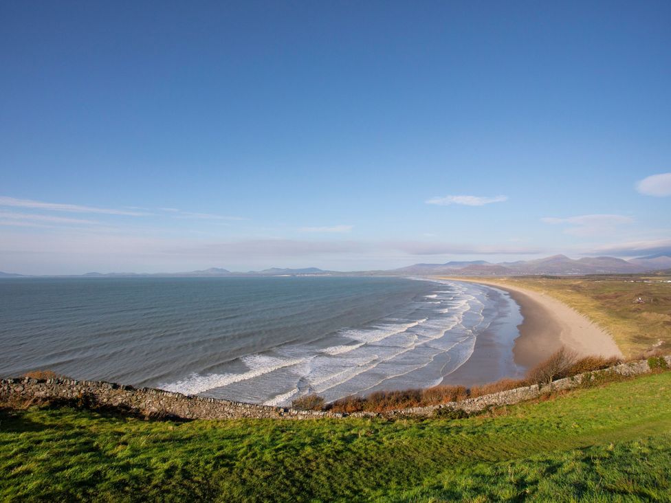 A view of the beach and sea with hills in the background at Redwood in Harlech
