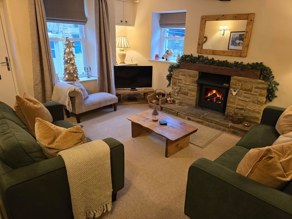 A living room with a fireplace and sofa at End Cottage in Grassington