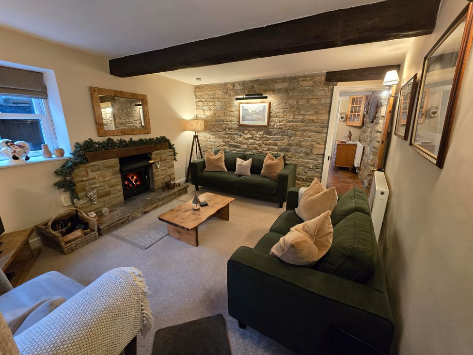 A living room with sofas and a fireplace at End Cottage in Grassington