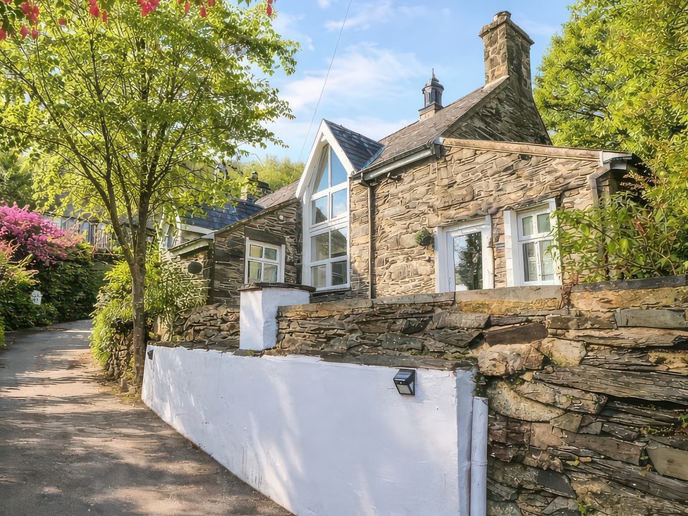 A house with stone walls and windows surrounded by trees at Yr Hen Ysgol, The Old School in Prenteg