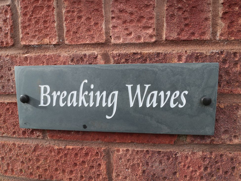 A sign displaying the name Breaking Waves on a brick wall in Burnham-On-Sea