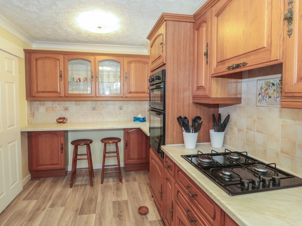 A kitchen with wooden cabinets and a gas stove at Breaking Waves in Burnham-On-Sea