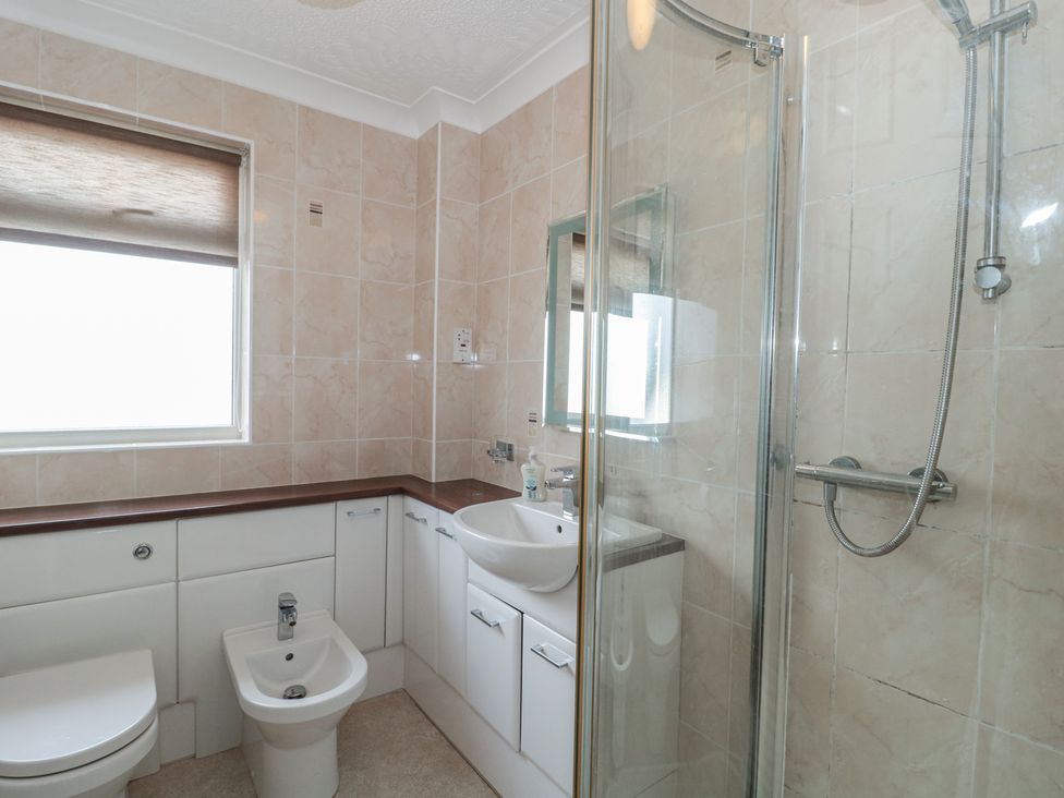 A bathroom with a shower, sink, toilet, and bidet at Breaking Waves in Burnham-On-Sea