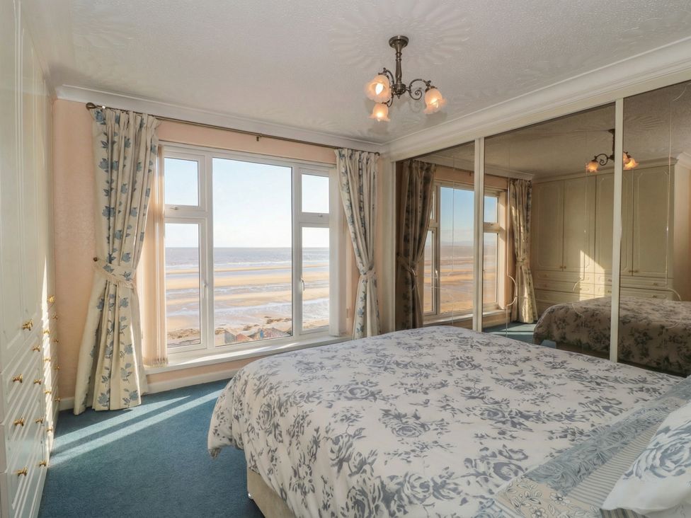 A bedroom with a bed and a view of the ocean at Breaking Waves in Burnham-On-Sea
