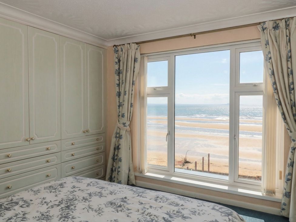 A bedroom with a window overlooking the beach at Breaking Waves in Burnham-On-Sea
